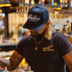 Bar staff member making a drink wearing our BSMC Garage Cap - Navy/White