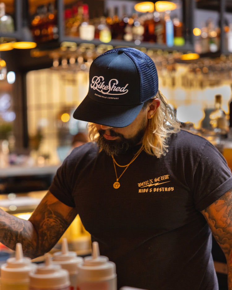 Bar staff member making a drink wearing our BSMC Garage Cap - Navy/White
