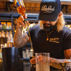 Bar staff member making a drink wearing our BSMC Garage Cap - Navy/White