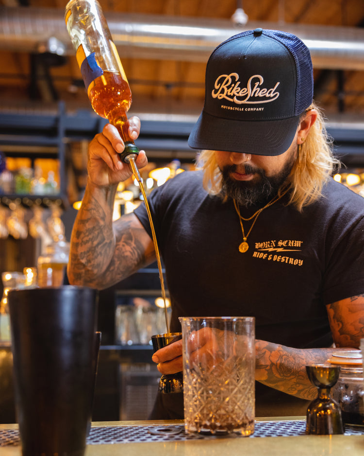 Bar staff member making a drink wearing our BSMC Garage Cap - Navy/White