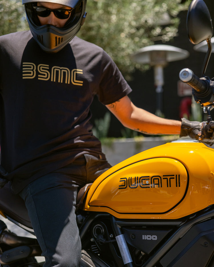 Model wearing BSMC '77 T shirt sitting on a Ducati Scrambler