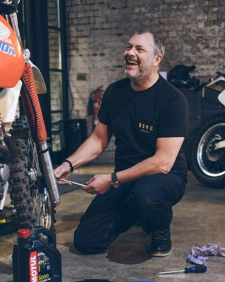 Dan working on his bike while wearing our BSMC ESTD. Pocket T Shirt - Black & Gold