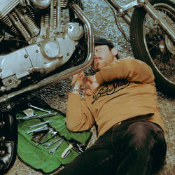 James working on his Harley while wearing our BSMC Garage Sweat - Tan/Black