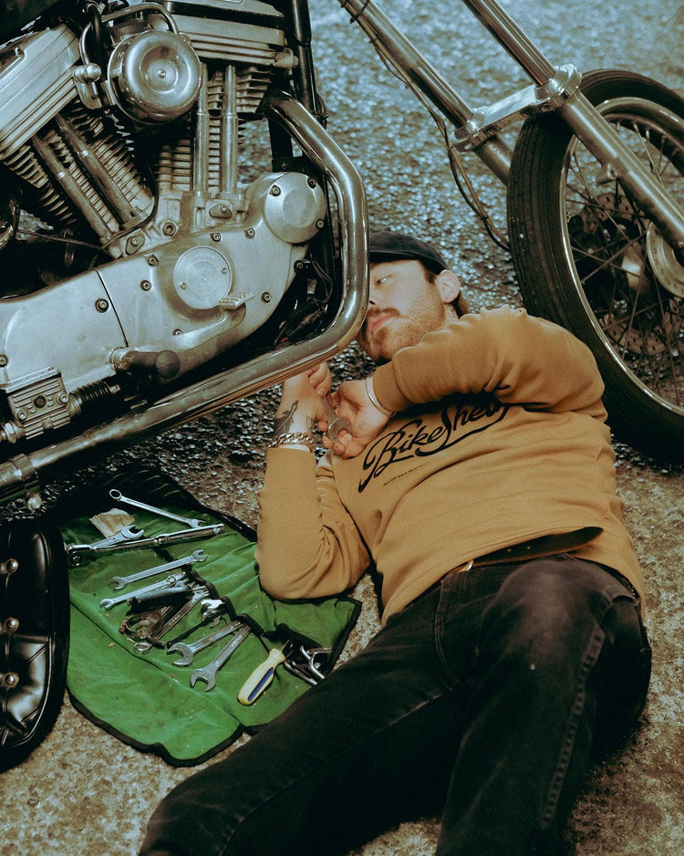 James working on his Harley while wearing our BSMC Garage Sweat - Tan/Black