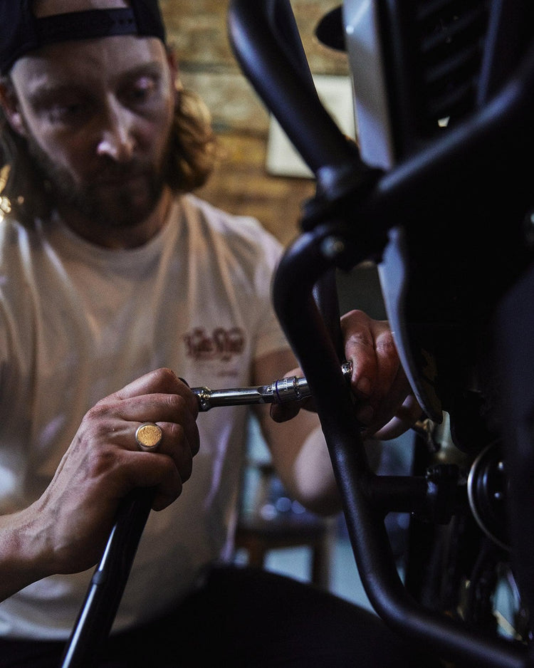 Gareth working on his bike while wearing our BSMC Handmade T Shirt - Cream