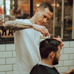 Luca wearing our BSMC Mural T Shirt - White cutting hair