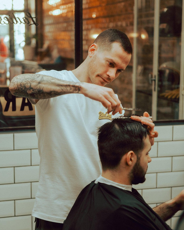Luca wearing our BSMC Mural T Shirt - White cutting hair
