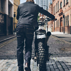 Model pushing his bike wearing our BSMC Protective - Road Jean - Raw Indigo
