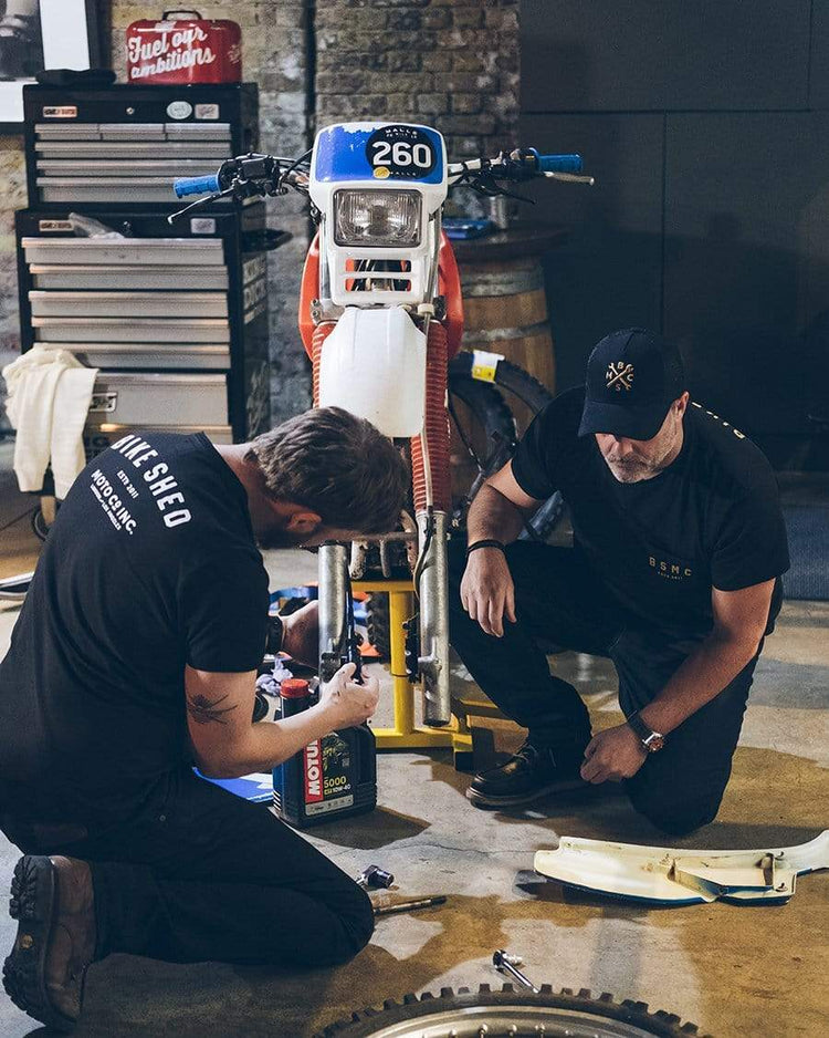 Dan working on his bike wearing our BSMC Spanners Cap - Black & Gold