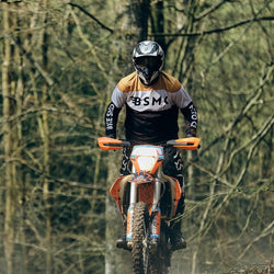 Dan riding in the forest wearing our BSMC Wing Race Jersey - Gold