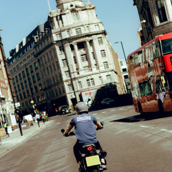 Steve riding past a London bus while wearing our BSMC Company T-Shirt - Navy