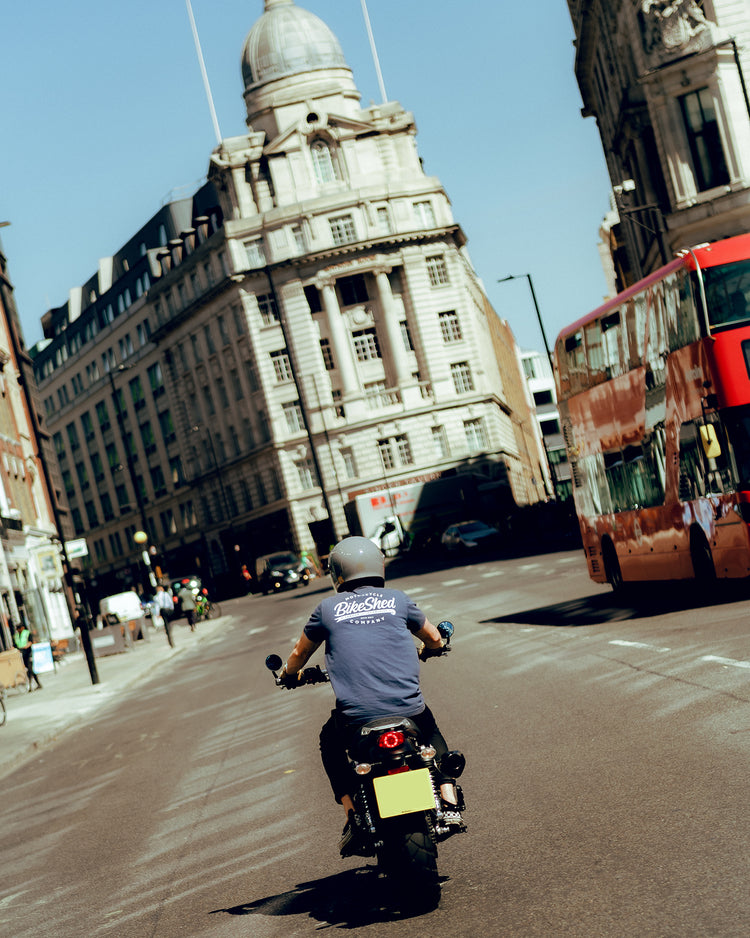 Steve riding past a London bus while wearing our BSMC Company T-Shirt - Navy