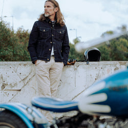 John standing near his Triumph wearing our BSMC Denim Jacket - Resistant Indigo