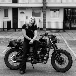 Model sitting on her bike wearing our BSMC Women's ESTD. Pocket T Shirt - Black