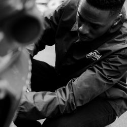 Model inspecting his bike wearing BSMC Company Coach Jacket - Black